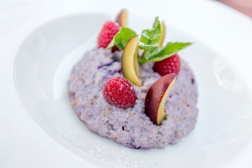 Oatmeal porridge with blueberries, raspberries and peach.