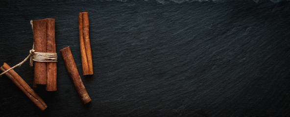 Cinnamon sticks on dark background, top view, text space