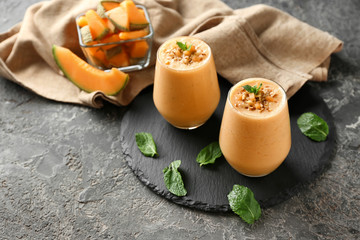 Glasses of tasty melon smoothie on grunge table