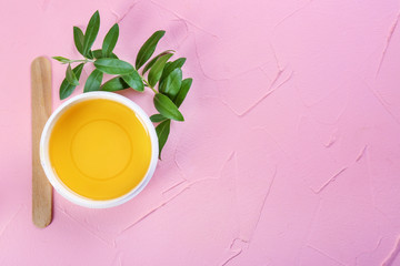 Plastic jar with sugaring paste and stick on color background