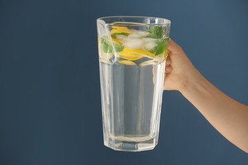 Woman holding jug of fresh lemonade on color background