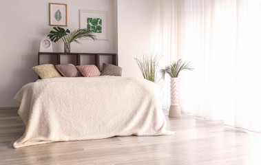 Interior of modern comfortable bedroom with tropical leaves