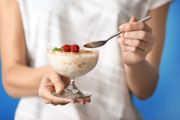 Woman eating delicious rice pudding with raspberry, closeup