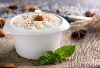 Bowl with delicious rice pudding and almond nuts on sackcloth