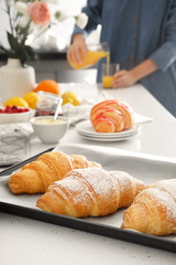 Baking tray with tasty croissants on light table in kitchen