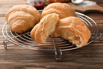 Tasty fresh croissants with cream on cooling rack