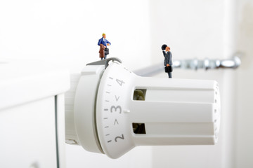 Radiator and small figurines. Businessman and consumer. Heating season concept. Heating battery.