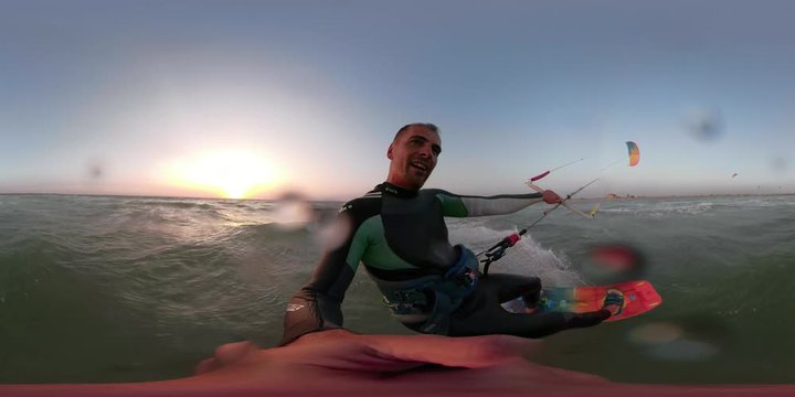 The men smile doing kitesurfing and holding a self-stick with a camera 360