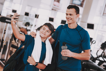 Fototapeta na wymiar Young Father and Son Taking Selfie near Treadmills