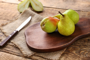 Wooden board with sweet ripe pears on table