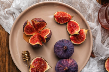 Plate with fresh ripe figs on wooden table