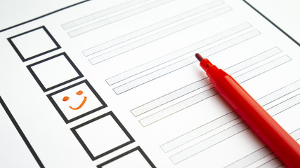 Voting in paper ballot by red pencil with smile