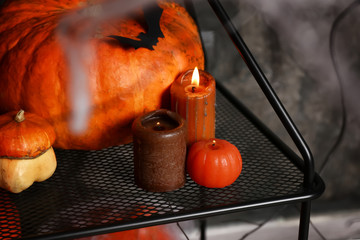 Burning candles with pumpkins as decor for Halloween party on stand