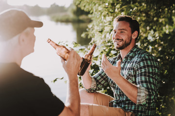 Smiling Men Drinking Beer near River in Summer.