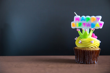 Cup cake and happy birthday text candle  on  cupcake ..Birthday cupcake with a happy brithday text...