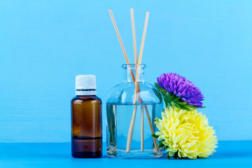 Air diffuser, essential and aroma oil bottles, flowers on a blue background. Aroma therapy, relaxation.