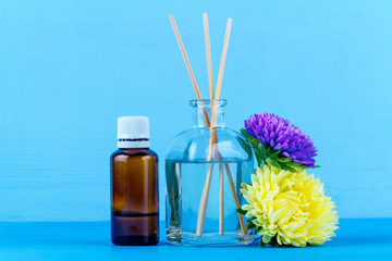 Air diffuser, essential and aroma oil bottles, flowers on a blue background. Aroma therapy, relaxation.