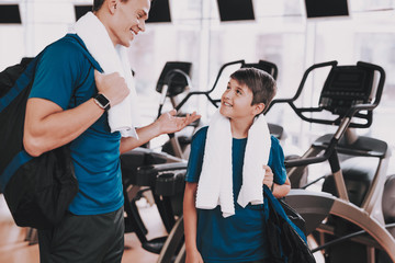 Fototapeta na wymiar Young Father and Son near Treadmills in Modern Gym