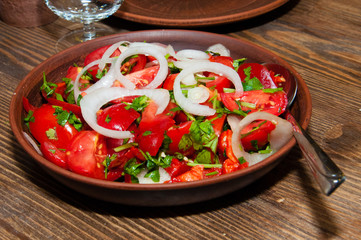 Salad of tomatoes, cucumbers, peppers, onions and greens dressed with olive, sunflower or corn oil in earthenware, wine glass