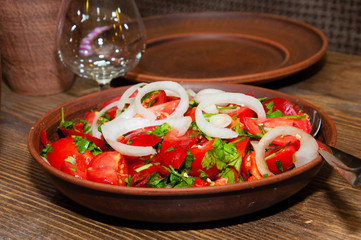 Salad of tomatoes, cucumbers, peppers, onions and greens dressed with olive, sunflower or corn oil in earthenware, wine glass, clay mug