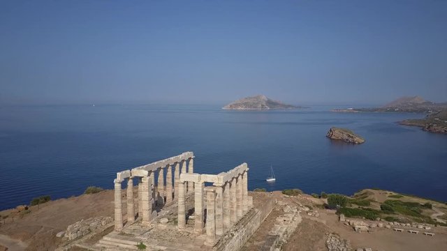 Greek temple of Poseidon in morning light. Aerial drone.Blue ocean sailing boats