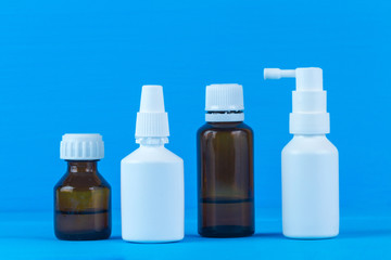 Fototapeta na wymiar Bottles and sprays with medicine for flu and colds on a blue background. Various drugs for the sore throat and stuffy nose. Treatment of colds