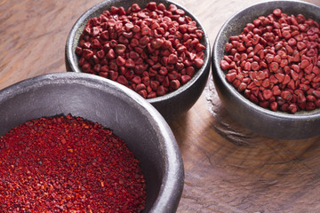 Annatto beans in bowl on wooden table