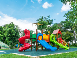 Colorful playground on yard in the park, playground for kids on trees and clouds background,