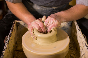 Professional male potter working with clay on potter's wheel in workshop, studio. Handmade, art and handicraft concept