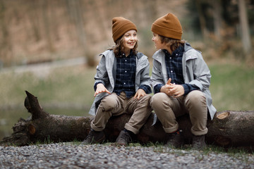 Fototapeta premium smiling boys talking while sitting on the big log