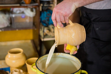 Professional male potter preparing ceramic wares for burning in pottery kiln with milk - old russian pottery tradition. Crafting, artwork and handmade concept