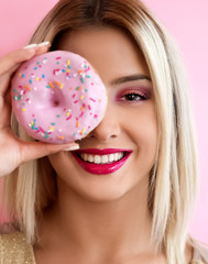 Young smiling woman holding pink donut