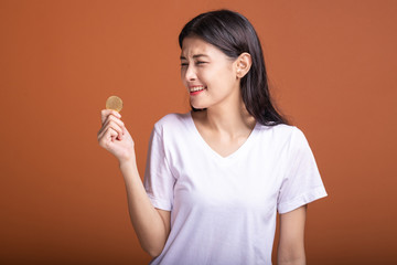 Woman holding bit coin isolated in orange background.