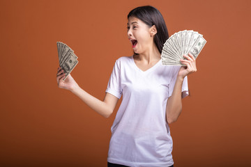 Woman holding cash notes isolated in orange background.