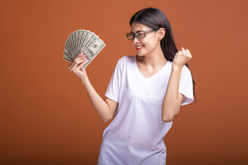 Woman holding cash notes isolated in orange background.