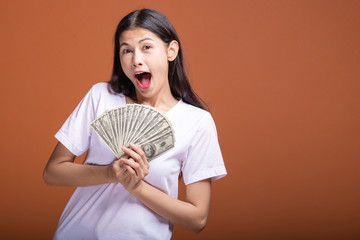 Woman holding cash notes isolated in orange background.