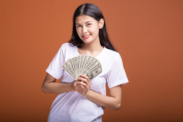 Woman holding cash notes isolated in orange background.