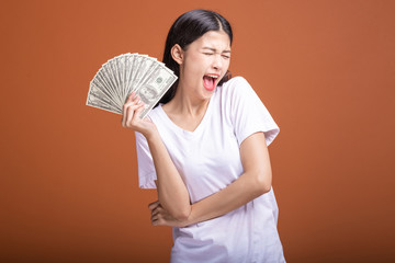 Woman holding cash notes isolated in orange background.