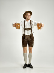 Portrait of Oktoberfest young man in hat, wearing a traditional Bavarian clothes standing with beer...