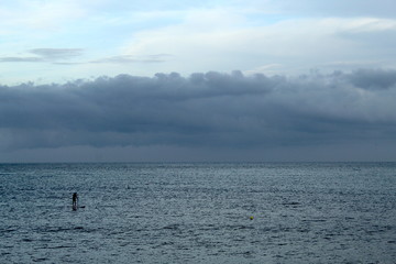 Obraz premium Man doing stand up paddle in the sea; cloudy day