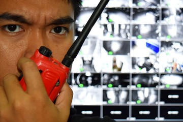 young asian man and red radio communication and blurred many channel all in one cctv monitor in...
