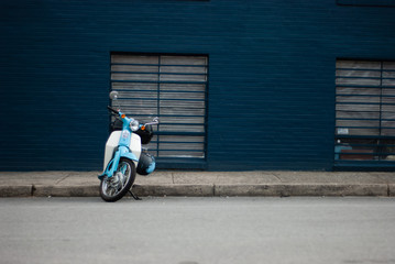 Blue scooter parked in front of a blue wall