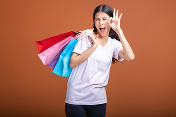 Woman holding shopping bag isolated in orange background.