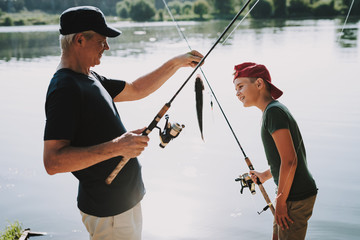 Happy Grandfather and Grandson Fishing on River.
