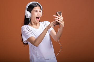 Woman using headphone isolated over orange background.