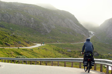 Fototapeta na wymiar A cyclist on mountain road in a fog, Norway