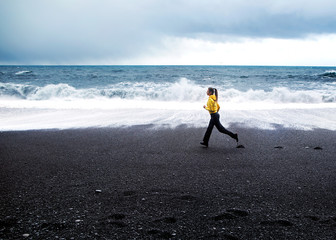 girl runs along the beach near the Atlantic Ocean in Iceland