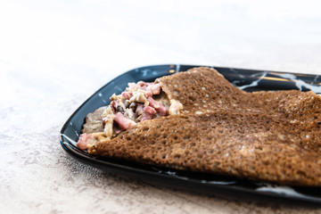 Black wheat and wheat galette topped with cooked ham and emmental cheese