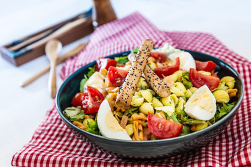 Salad of pasta, egg, smoked salmon tartare, salad and tomato, with a citrus vinaigrette sauce.