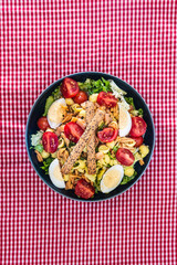 Salad of pasta, egg, smoked salmon tartare, salad and tomato, with a citrus vinaigrette sauce.